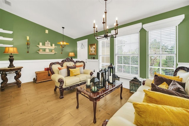 living room with a notable chandelier, vaulted ceiling, and light wood-type flooring