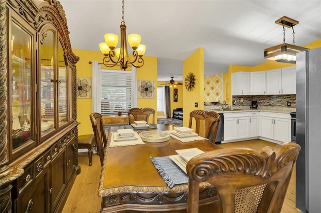 dining room featuring sink, light hardwood / wood-style flooring, and ceiling fan with notable chandelier