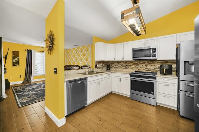 kitchen with white cabinetry, light hardwood / wood-style floors, appliances with stainless steel finishes, and lofted ceiling