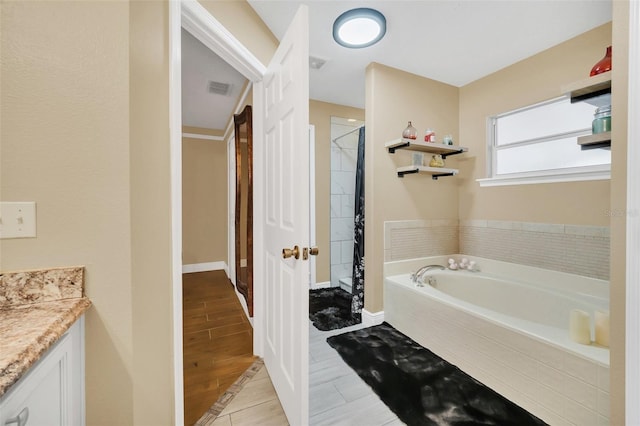 bathroom featuring vanity, a relaxing tiled tub, hardwood / wood-style floors, and ornamental molding