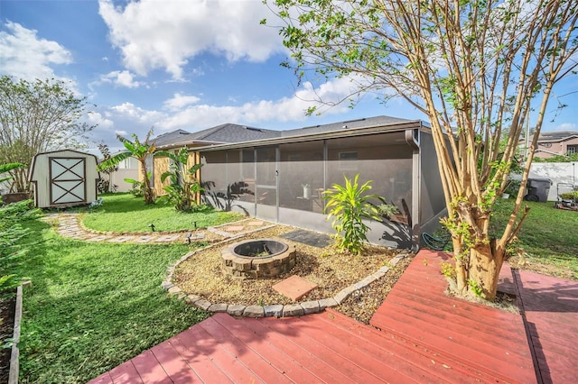 view of yard with a shed, a fire pit, a deck, and a sunroom