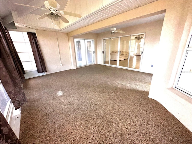 unfurnished living room featuring beam ceiling, a healthy amount of sunlight, ceiling fan, and carpet flooring