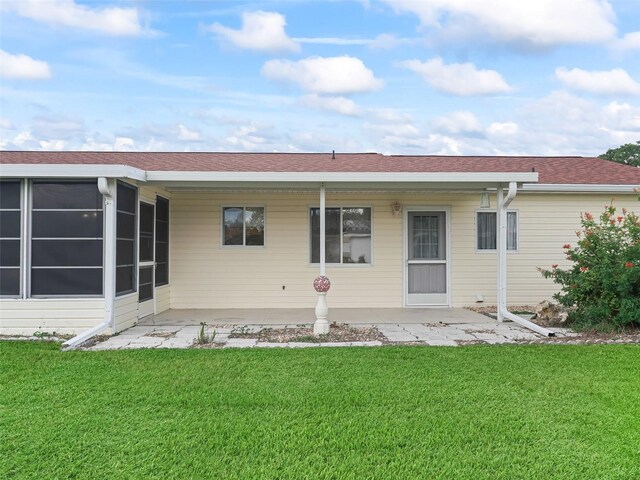 rear view of property featuring a yard and a sunroom