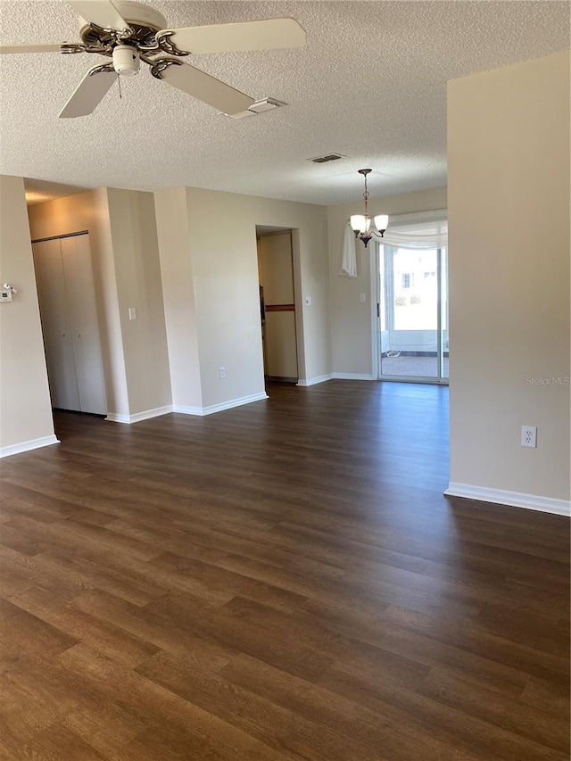 unfurnished room with ceiling fan with notable chandelier, dark wood-type flooring, and a textured ceiling