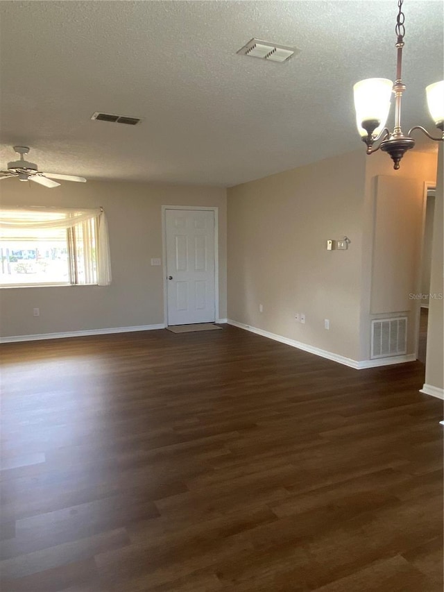 unfurnished room with ceiling fan with notable chandelier, a textured ceiling, and dark hardwood / wood-style flooring