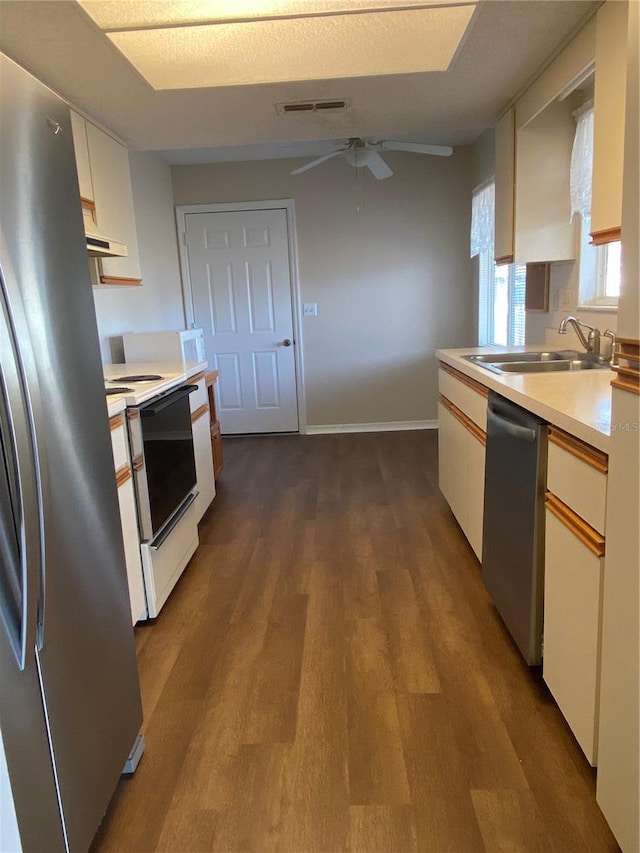 kitchen featuring ceiling fan, dark hardwood / wood-style floors, sink, appliances with stainless steel finishes, and white cabinets