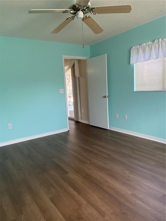 empty room with ceiling fan, dark hardwood / wood-style flooring, and a textured ceiling