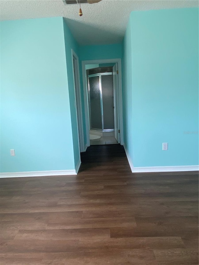 unfurnished room with a textured ceiling and dark wood-type flooring