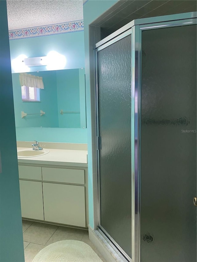 bathroom with a shower with shower door, tile patterned floors, and vanity