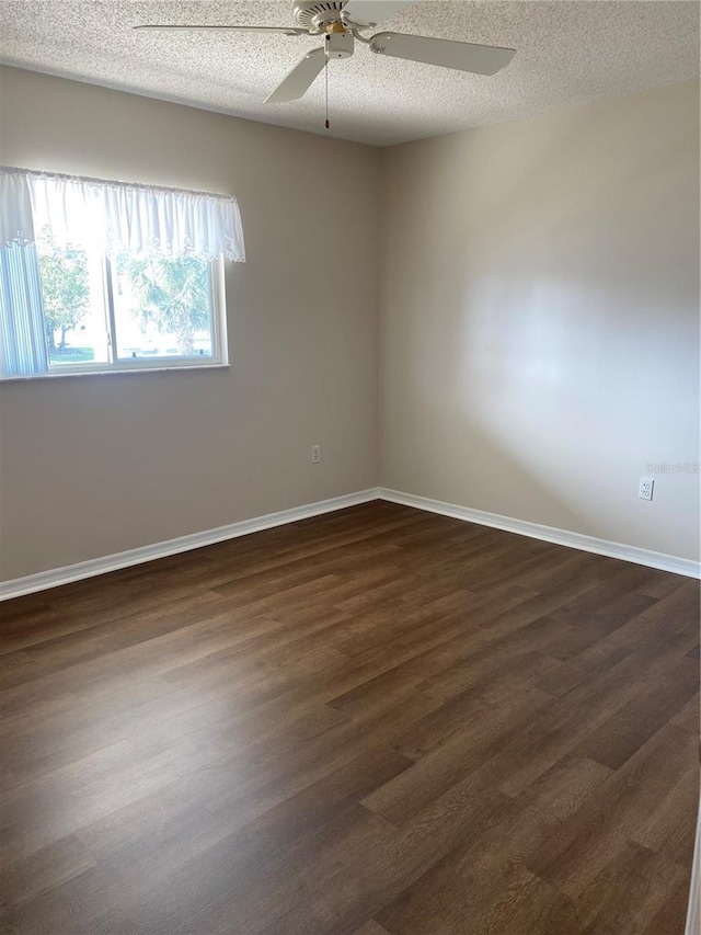 empty room with ceiling fan, dark wood-type flooring, and a textured ceiling