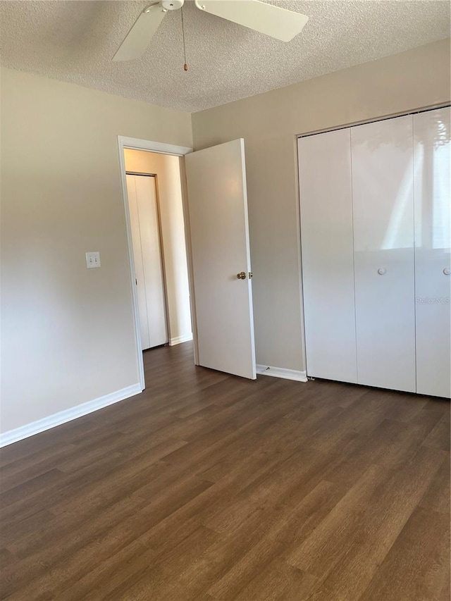 unfurnished bedroom featuring ceiling fan, a closet, dark hardwood / wood-style flooring, and a textured ceiling