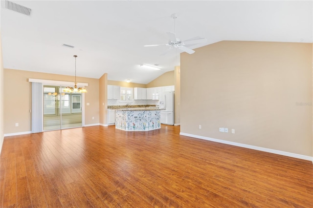 unfurnished living room featuring ceiling fan with notable chandelier, light hardwood / wood-style floors, and vaulted ceiling