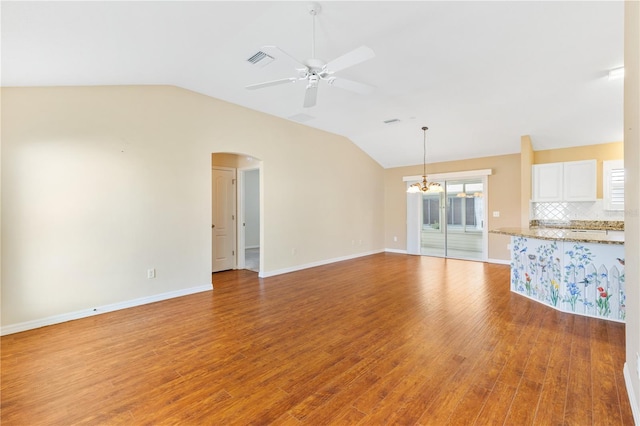 unfurnished living room with light wood-type flooring, ceiling fan with notable chandelier, and vaulted ceiling