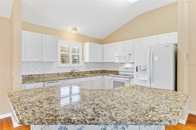 kitchen with light stone countertops, sink, a kitchen island, white appliances, and white cabinets