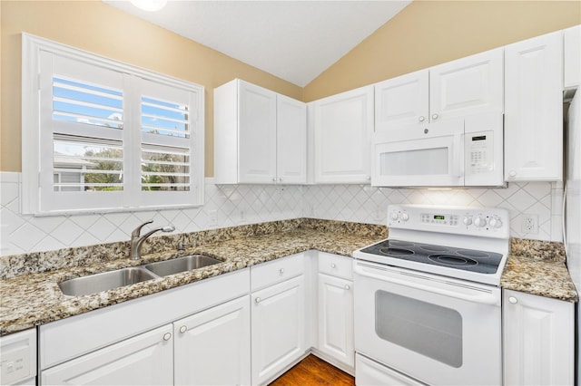 kitchen with white appliances, sink, dark stone countertops, white cabinetry, and lofted ceiling