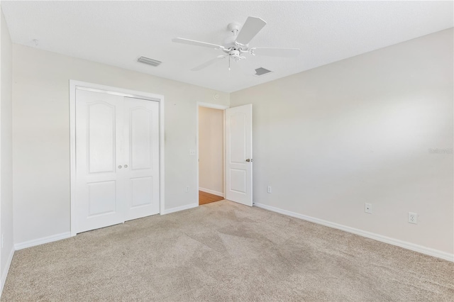 unfurnished bedroom with ceiling fan, light colored carpet, and a closet