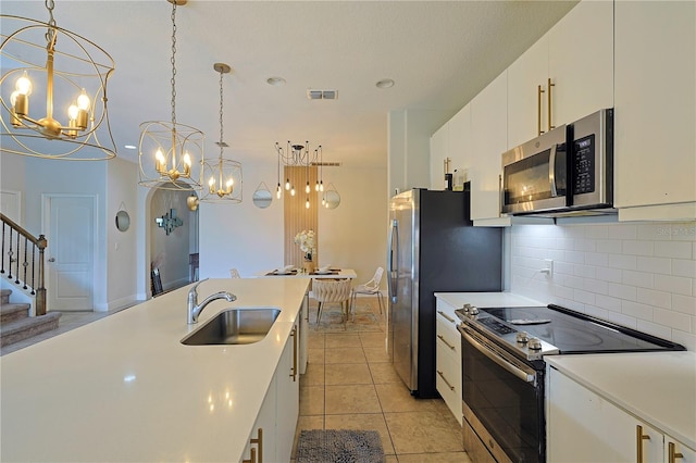 kitchen with white cabinets, hanging light fixtures, light tile patterned floors, sink, and stainless steel appliances