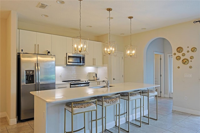 kitchen featuring appliances with stainless steel finishes, white cabinetry, sink, and a center island with sink