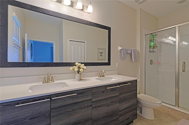 bathroom featuring a shower with door, vanity, toilet, and tile patterned floors