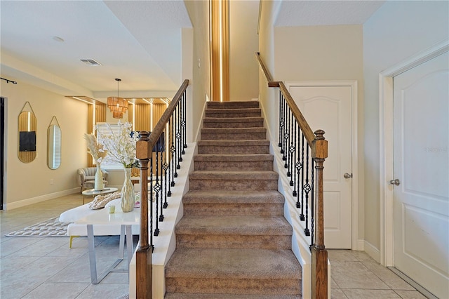 stairs with a notable chandelier and tile patterned flooring