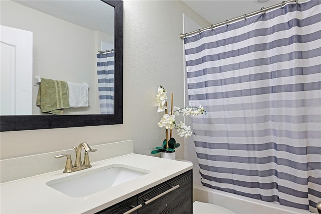 full bathroom with vanity, shower / tub combo with curtain, a textured ceiling, and toilet