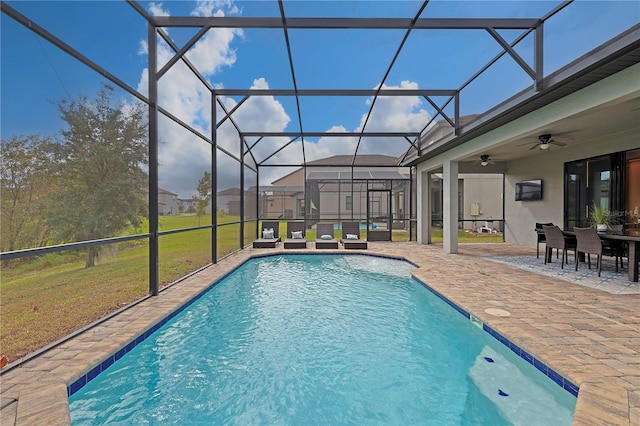 view of swimming pool with ceiling fan, glass enclosure, a patio area, and a lawn