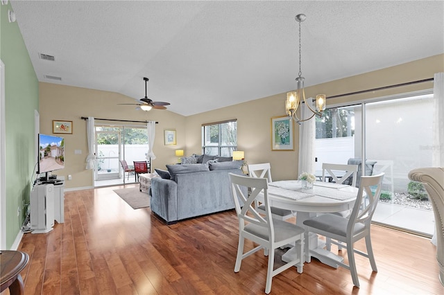 dining area featuring lofted ceiling, hardwood / wood-style floors, a textured ceiling, and ceiling fan with notable chandelier