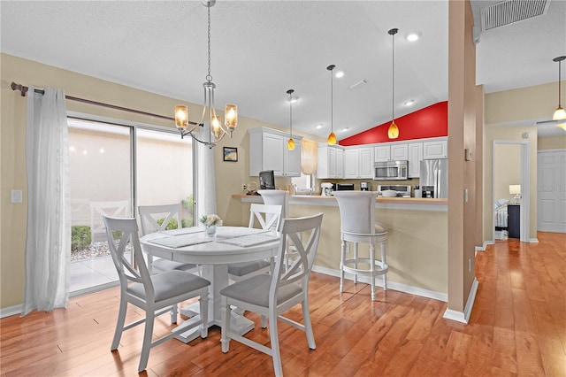 dining room with light hardwood / wood-style floors, a notable chandelier, a textured ceiling, and lofted ceiling