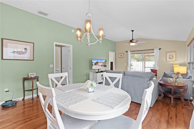 dining room featuring vaulted ceiling, wood-type flooring, and ceiling fan with notable chandelier