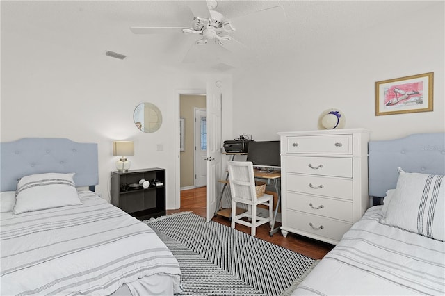 bedroom with a textured ceiling, dark wood-type flooring, and ceiling fan