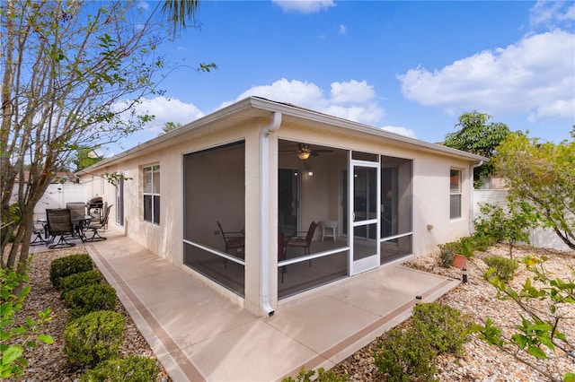 rear view of property with ceiling fan, a patio area, and a sunroom