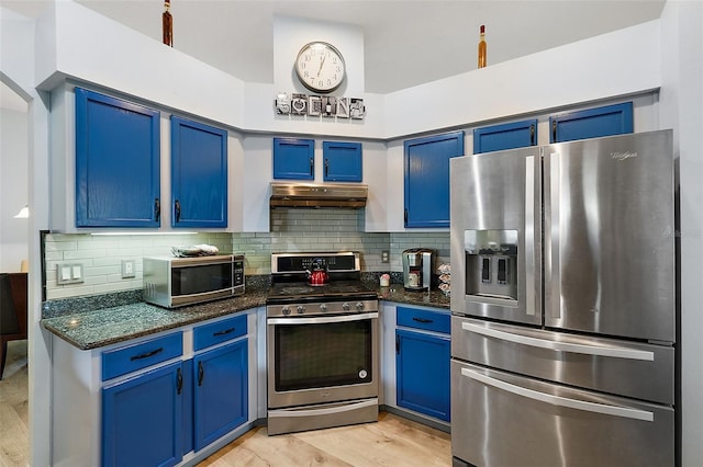 kitchen with appliances with stainless steel finishes, light wood-type flooring, blue cabinets, and dark stone countertops