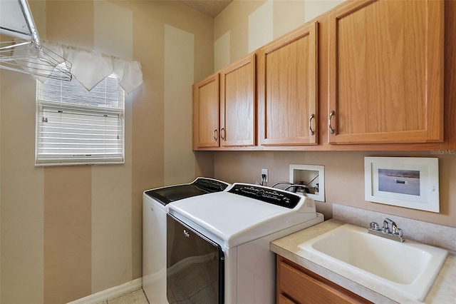 laundry room featuring washing machine and clothes dryer, cabinets, and sink