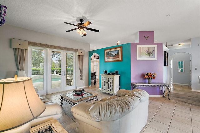 tiled living room with french doors, a textured ceiling, and ceiling fan