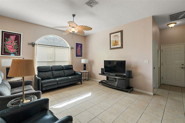 living room featuring a textured ceiling, ceiling fan, and light tile patterned flooring