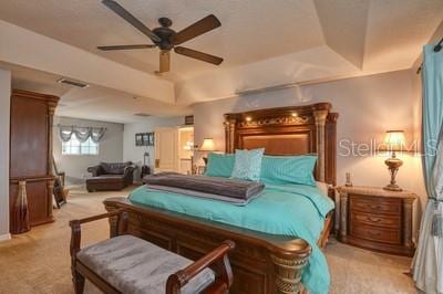 bedroom with a tray ceiling and light carpet