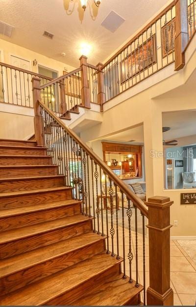 stairs featuring tile patterned flooring, a high ceiling, and a textured ceiling