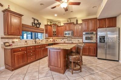 kitchen featuring appliances with stainless steel finishes, a breakfast bar, backsplash, a kitchen island, and ceiling fan