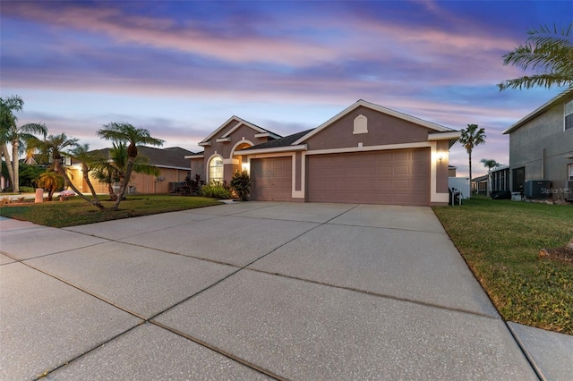 ranch-style house with central AC, a garage, and a lawn