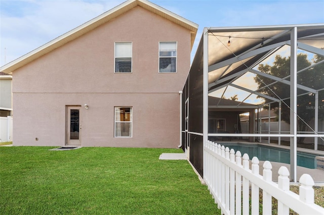 rear view of house featuring a yard and glass enclosure