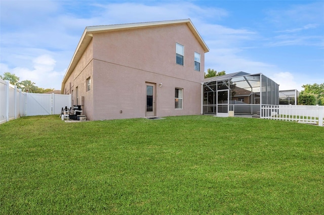 rear view of house featuring a lanai and a yard