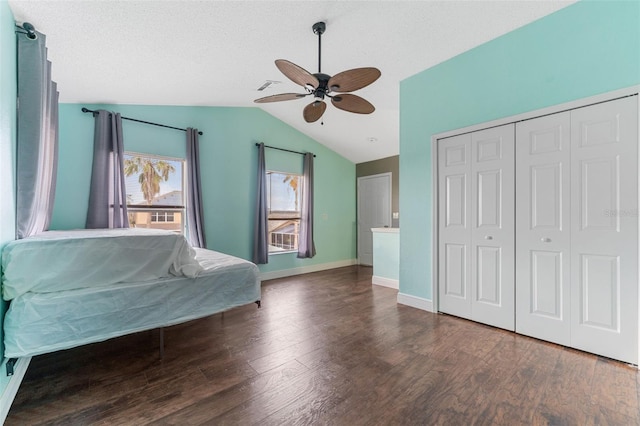 unfurnished bedroom featuring lofted ceiling, ceiling fan, a textured ceiling, dark wood-type flooring, and a closet