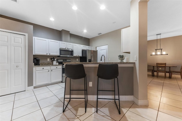 kitchen featuring a kitchen breakfast bar, appliances with stainless steel finishes, white cabinetry, and stone countertops