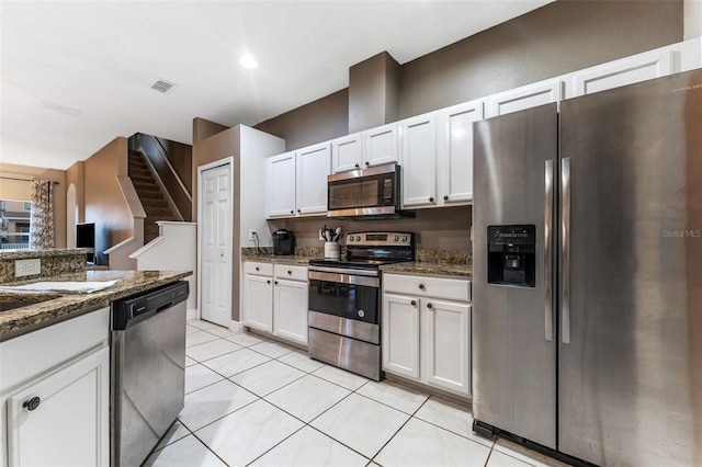 kitchen featuring appliances with stainless steel finishes, white cabinets, and dark stone countertops