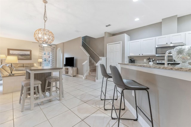 kitchen with a breakfast bar area, light stone countertops, decorative light fixtures, an inviting chandelier, and white cabinets