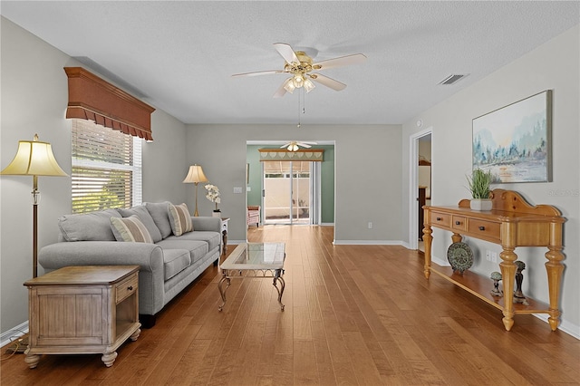 living room with hardwood / wood-style floors, ceiling fan, and a textured ceiling