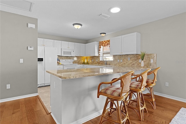 kitchen with white appliances, light hardwood / wood-style floors, and kitchen peninsula