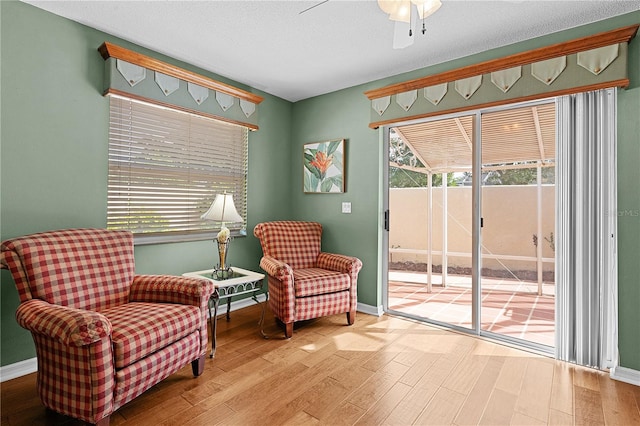 living area with hardwood / wood-style flooring, ceiling fan, and a textured ceiling