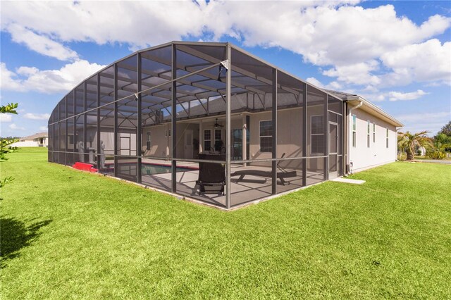 back of house featuring a patio area, a lawn, and glass enclosure