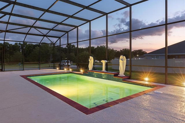 pool at dusk featuring a patio and a lanai